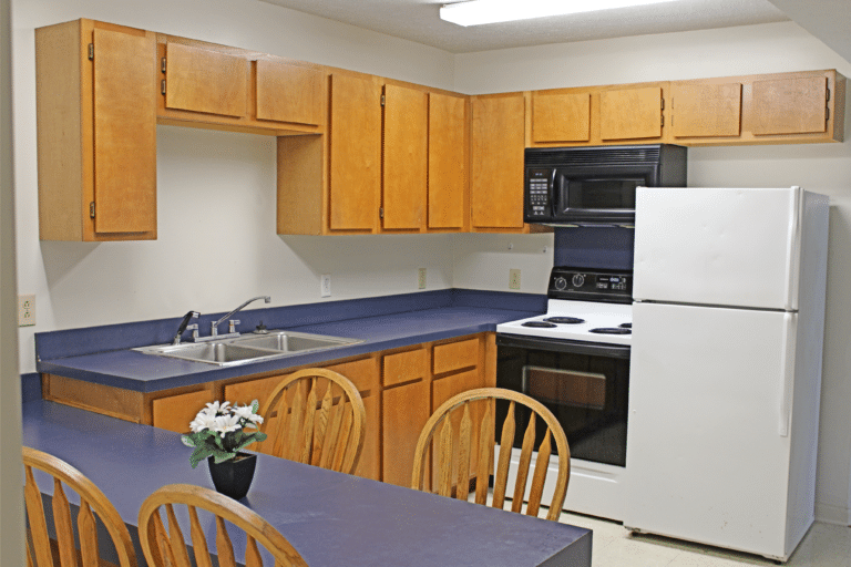 年轻的大厅公寓内的厨房. 有冰箱、炉子、微波炉、水槽和桌子.